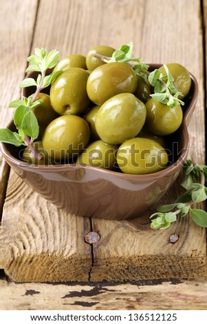 green marinated olives with oregano on a wooden background