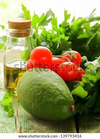 still life of fresh vegetables (avocado, tomato) olive oil and herbs