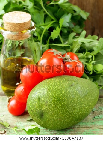 still life of fresh vegetables (avocado, tomato) olive oil and herbs