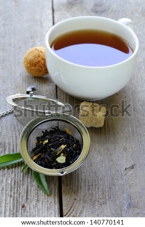 black tea leaves in a metal strainer on a wooden table