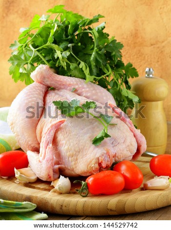 fresh raw chicken on a cutting board with vegetables
