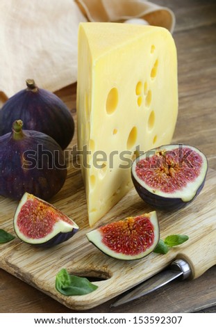 piece of cheese (Maasdam) with fresh figs on a wooden board