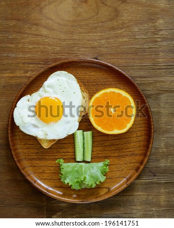 funny face serving breakfast, fried egg, toast and green salad
