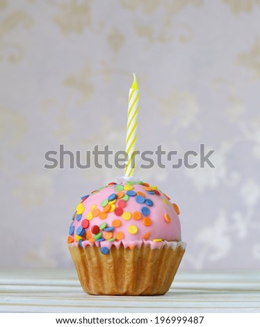 birthday cupcake with a candle on a vintage background