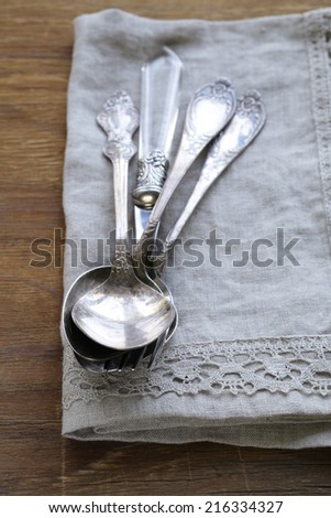 vintage silver cutlery with linen napkin on wooden background