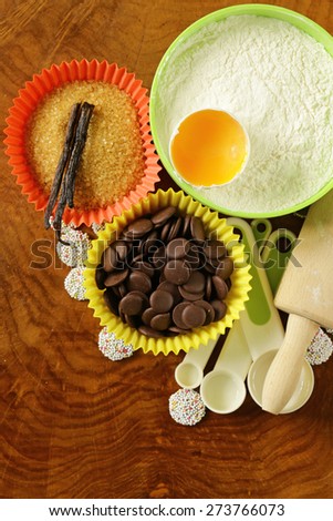 Baking ingredients (sugar, vanilla, flour, egg, chocolate) on a wooden table