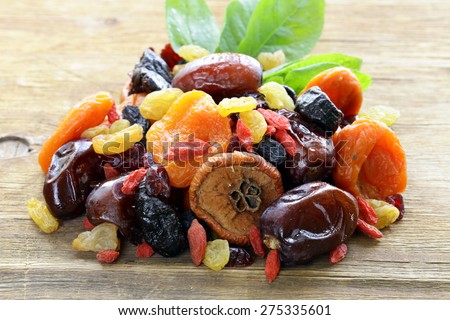 Assorted dried fruits (raisins, apricots, figs, prunes, goji, cranberries) on a wooden background