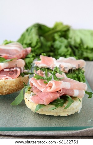 sandwiches with ham and arugula on a glass board