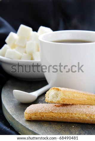 A cup of black coffee and refined sugar on a black background