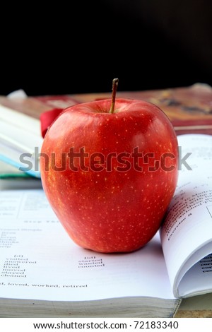 red ripe apple with English textbooks on a black background