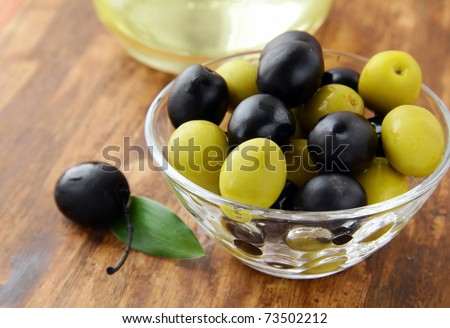 black and green olives and a bottle of olive oil on brown board