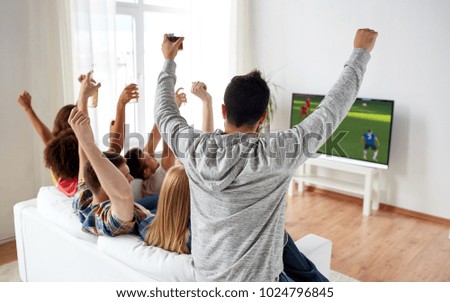 football, leisure and people concept - happy friends with drinks watching soccer game on tv at home and celebrating victory