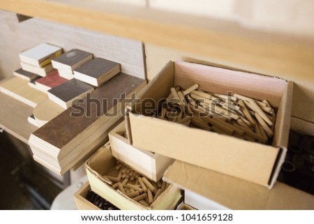furniture production, manufacture and woodworking industry concept - wood dowel pins and board samples at workshop