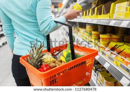 sale, shopping, consumerism and people concept - woman with food basket and jar at grocery store or supermarket