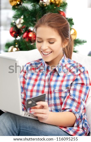 happy woman with laptop computer and credit card over christmas tree....