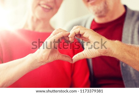 relationships, love and old people concept - close up of senior couple showing hand heart gesture