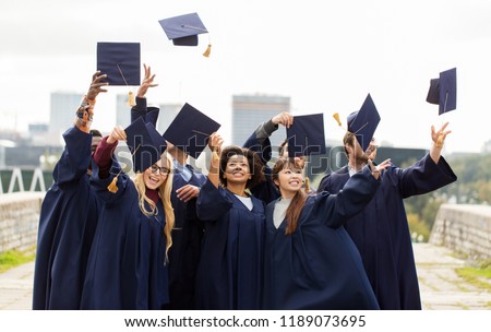 education, graduation and people concept - group of happy international students in bachelor gowns throwing mortar boards up in the air