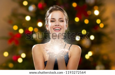 magic and holidays concept - beautiful woman with fairy dust over christmas lights background