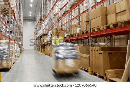 logistic business, shipment and loading concept - motion blurred picture of worker carrying loader with goods at warehouse