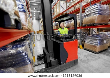 logistic business, shipment and loading concept - male loader operating forklift at warehouse