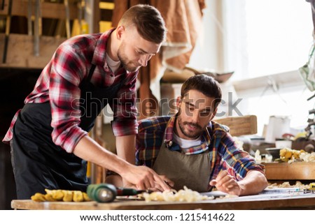 profession, carpentry, woodwork and people concept - two carpenters working at workshop
