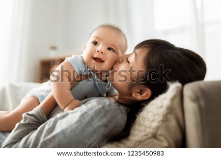 family and motherhood concept - happy young asian mother kissing little baby son at home