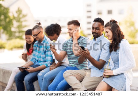 technology, friendship and international concept - group of friends with smartphones hanging out in summer city