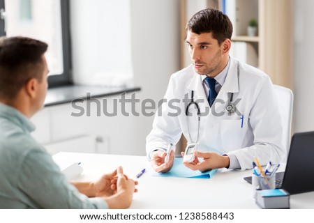 medicine, healthcare and diabetes concept - doctor with glucometer and insulin pen device talking to male patient at medical office in hospital