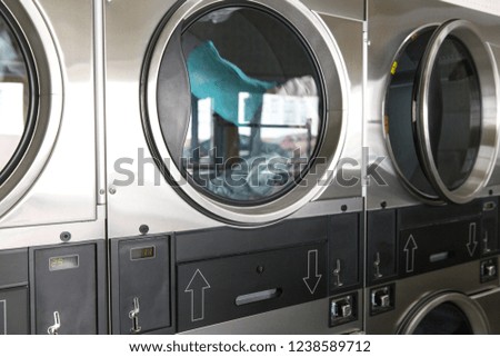 self-service laundry facilities concept - washing machines with clothes inside at laundromat