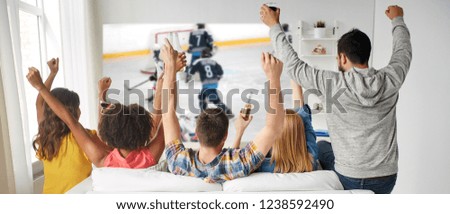friendship, sport and leisure concept - happy friends drinking beer and watching ice hockey game on projector screen at home