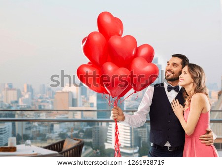 valentines day, love and people concept - happy couple with red heart shaped balloons over restaurant lounge in singapore city background