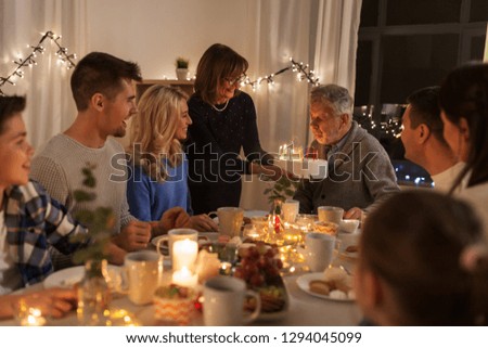 celebration and family concept - happy grandfather blowing candles on birthday cake at dinner party at home