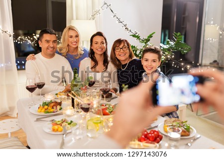 celebration, holidays and people concept - happy family having dinner party at home and photographing by smartphone
