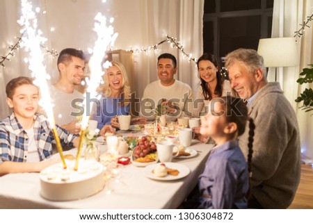 celebration, birthday and people concept - happy family having dinner party with fountain fireworks or sparkler candles burning on cake at home