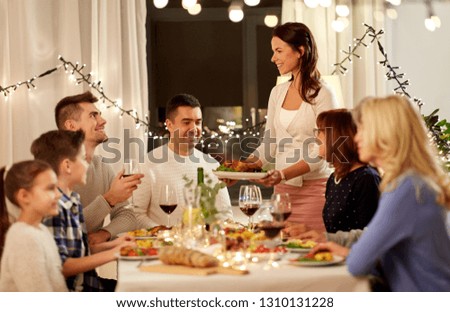 celebration, holidays and people concept - happy woman offering roast chicken to family having dinner party at home