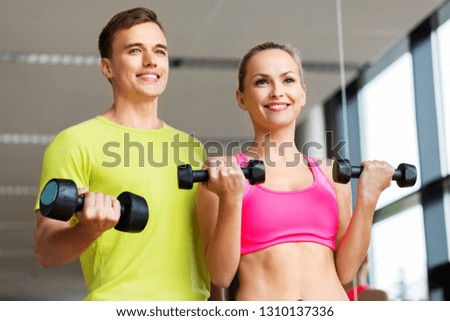 sport, fitness and people concept - couple with dumbbells exercising in gym