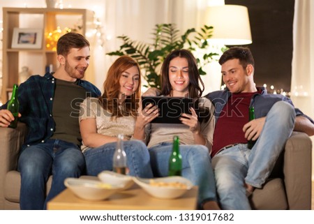 friendship, people, technology and entertainment concept - happy friends with tablet computer, snacks and non-alcoholic beer at home in evening