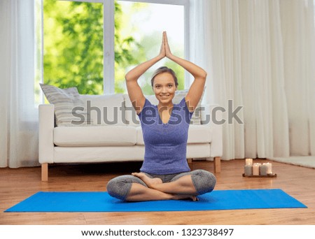 mindfulness, spirituality and healthy lifestyle concept - woman meditating in lotus pose at home