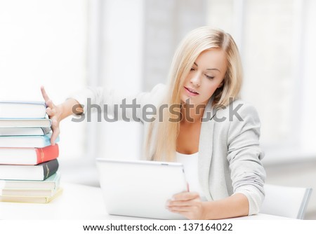 student with tablet pc pushing away stack of books