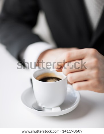 close up of man putting sugar into coffee