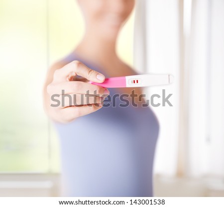 close up of woman holding pregnancy test