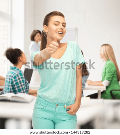 smiling girl in color t-shirt showing thumbs up at school