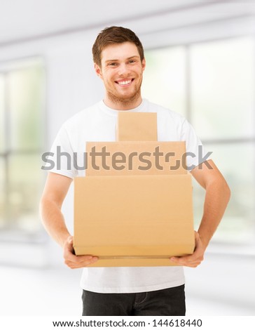 picture of smiling man carrying carton boxes at home