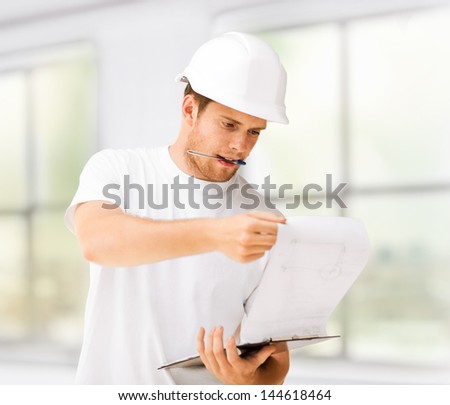 male architect in helmet looking at blueprint at home