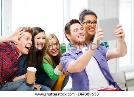 education and technology - group of students making picture with tablet pc at school - stock photo