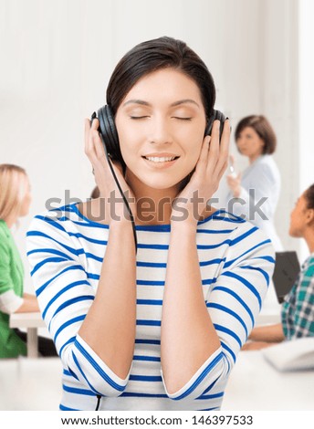 education and music concept - student girl in big headphones at school