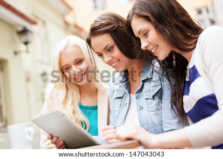 holidays tourism and internet beautiful girls looking at tablet pc in cafe outside holidays tourism and internet beautiful girls looking at tablet pc in cafe outside