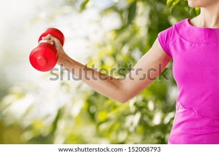 holidays, sport and recreation concept - sporty woman hands with light red dumbbells