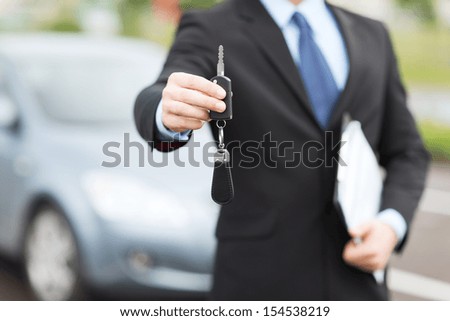 transportation and ownership concept - man with car key outside