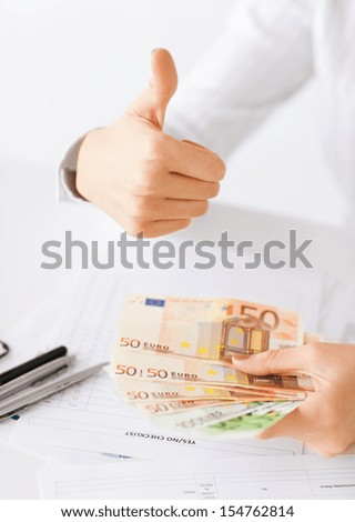 business, office, household, banking, tax, gambling concept - woman hands with euro cash money and thumbs up